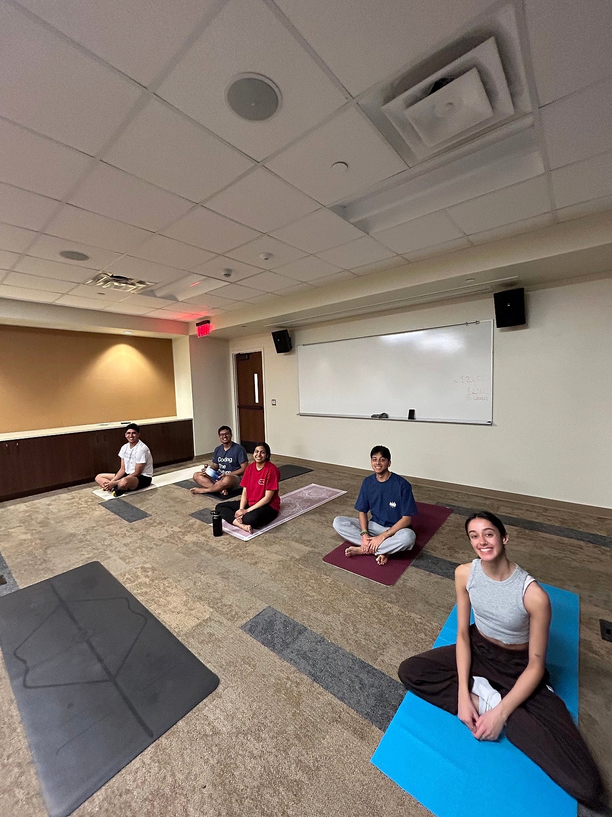 A small class seated on mats in a classroom