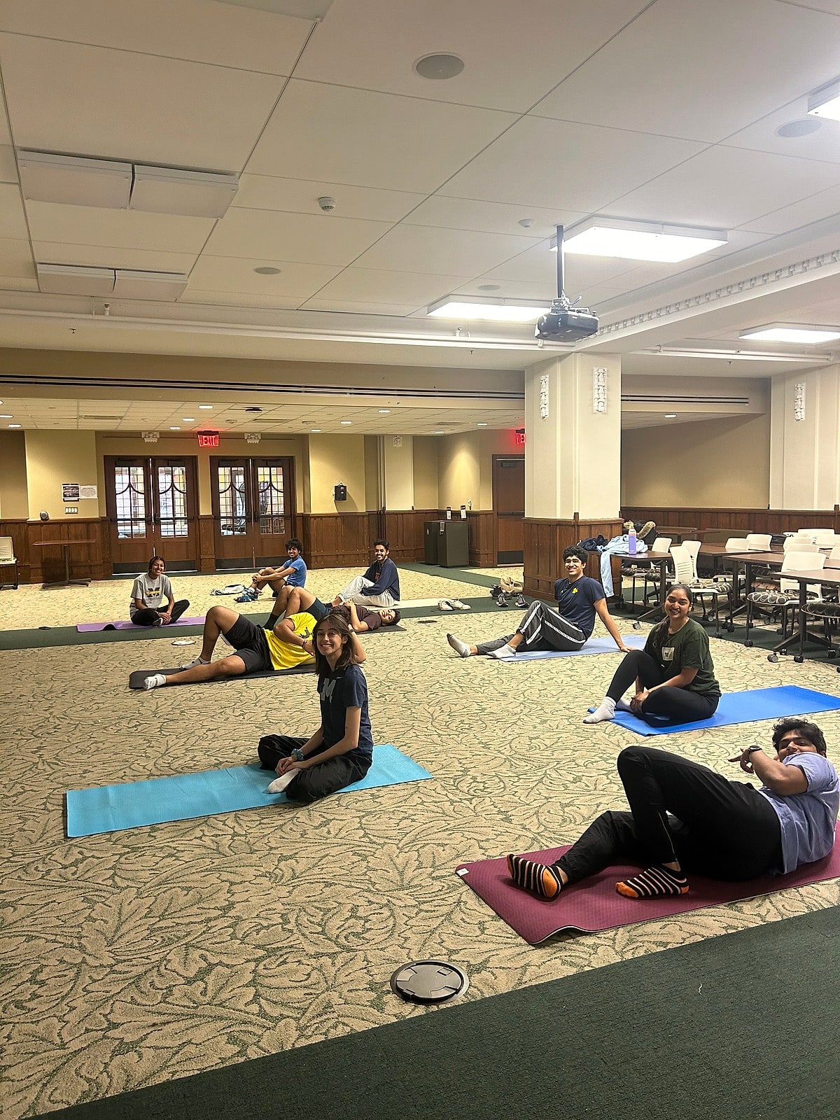 Students stretching on mats in a carpeted hall