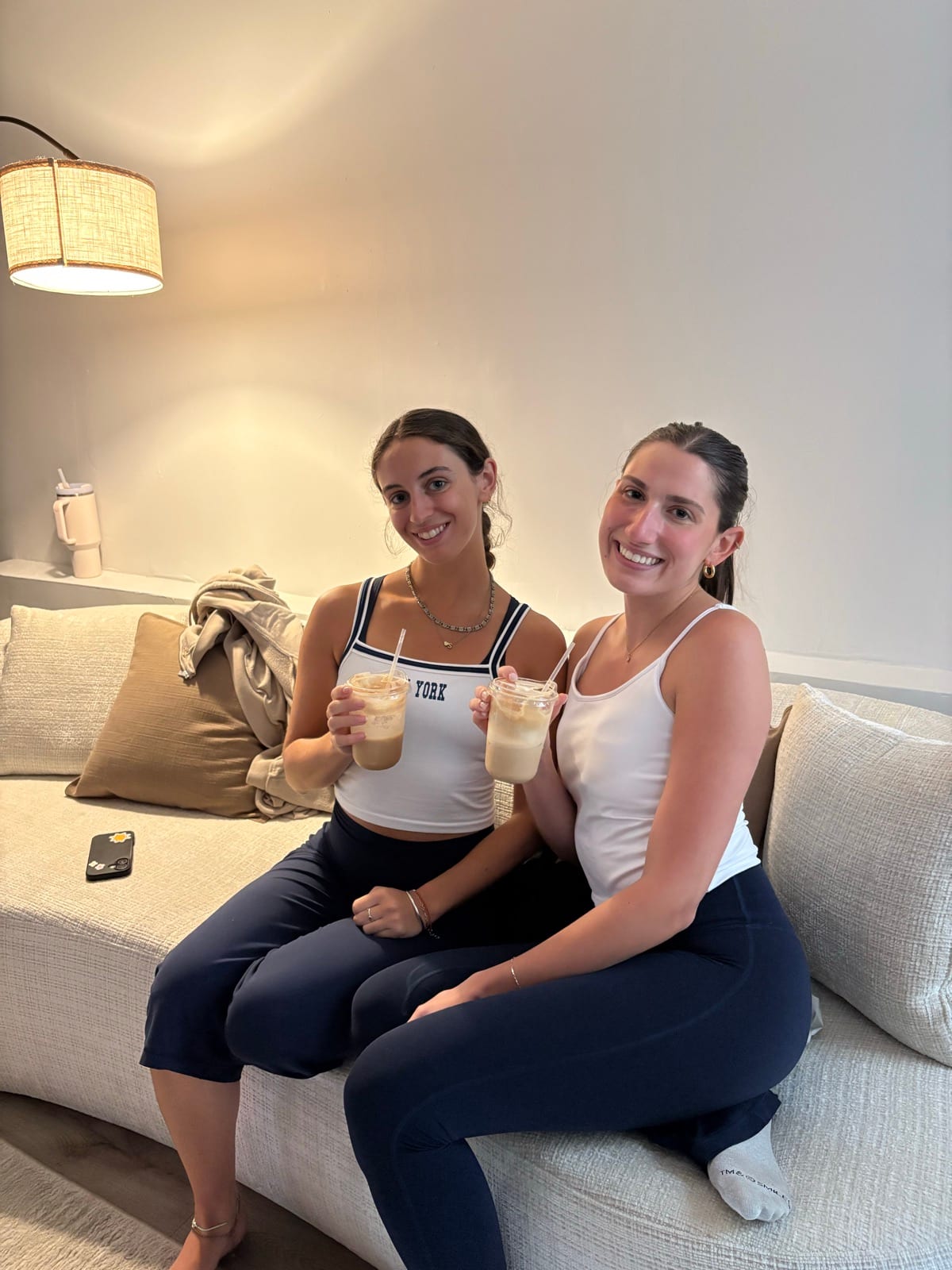 Two guests sitting on a sofa with their iced coffees
