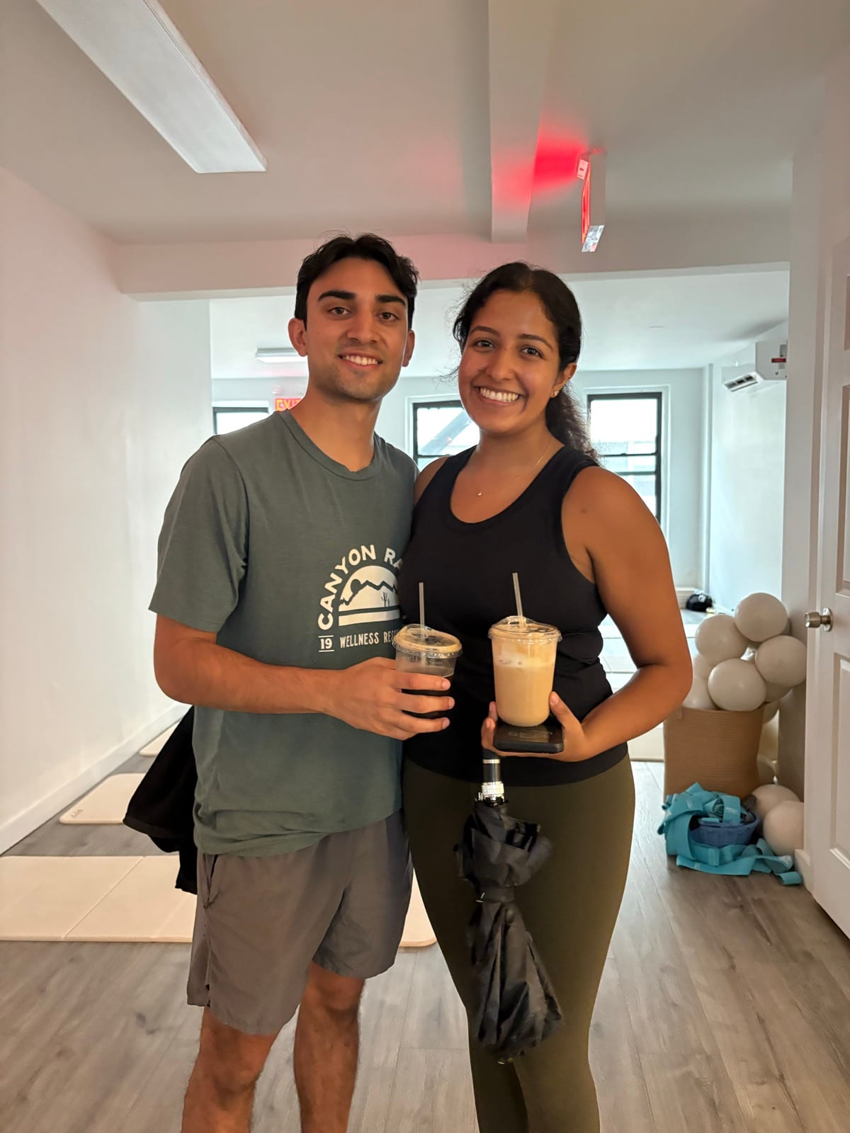 Two guests standing together in the studio holding iced coffees