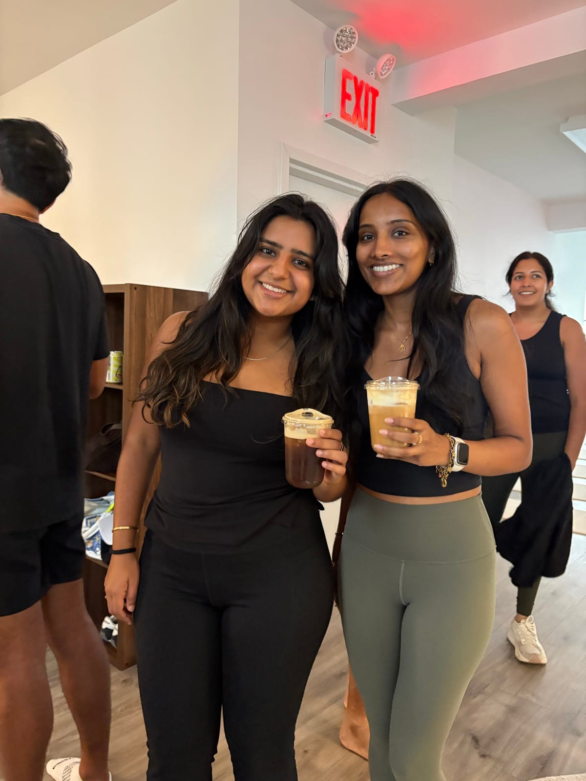 Two guests smiling with their drinks while others chat in the background