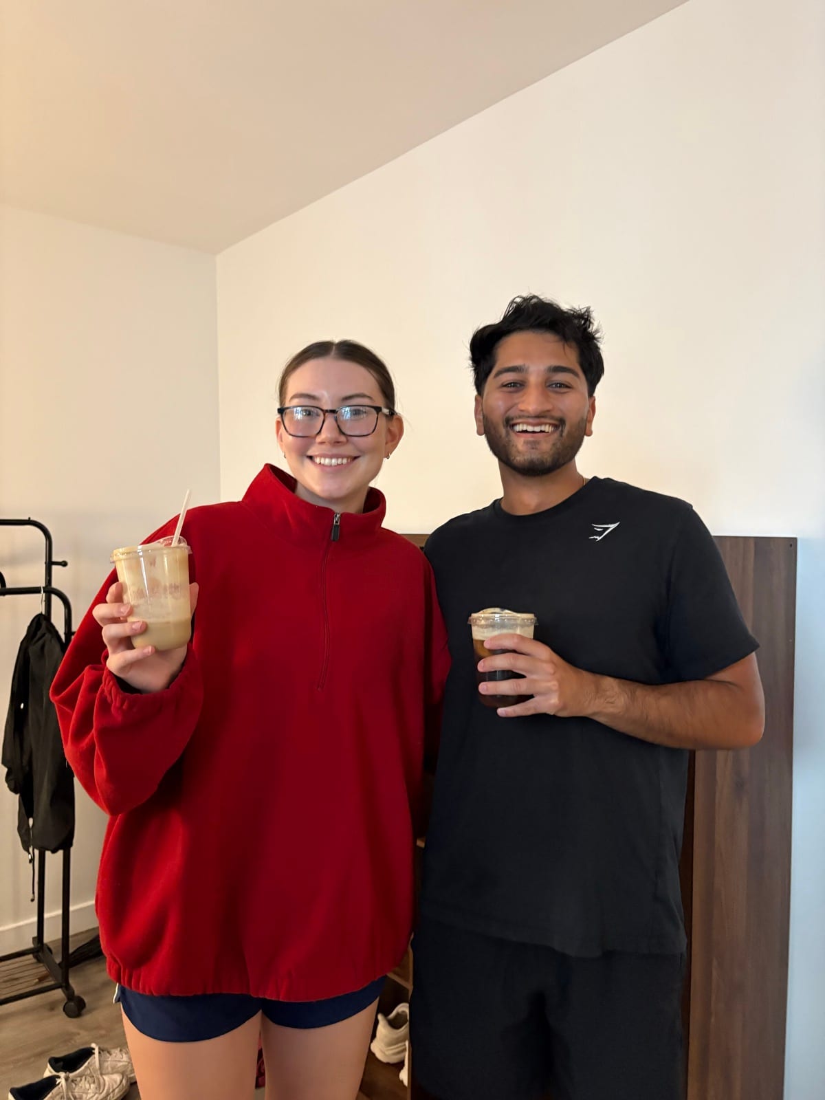 Two guests posing with iced coffees after class