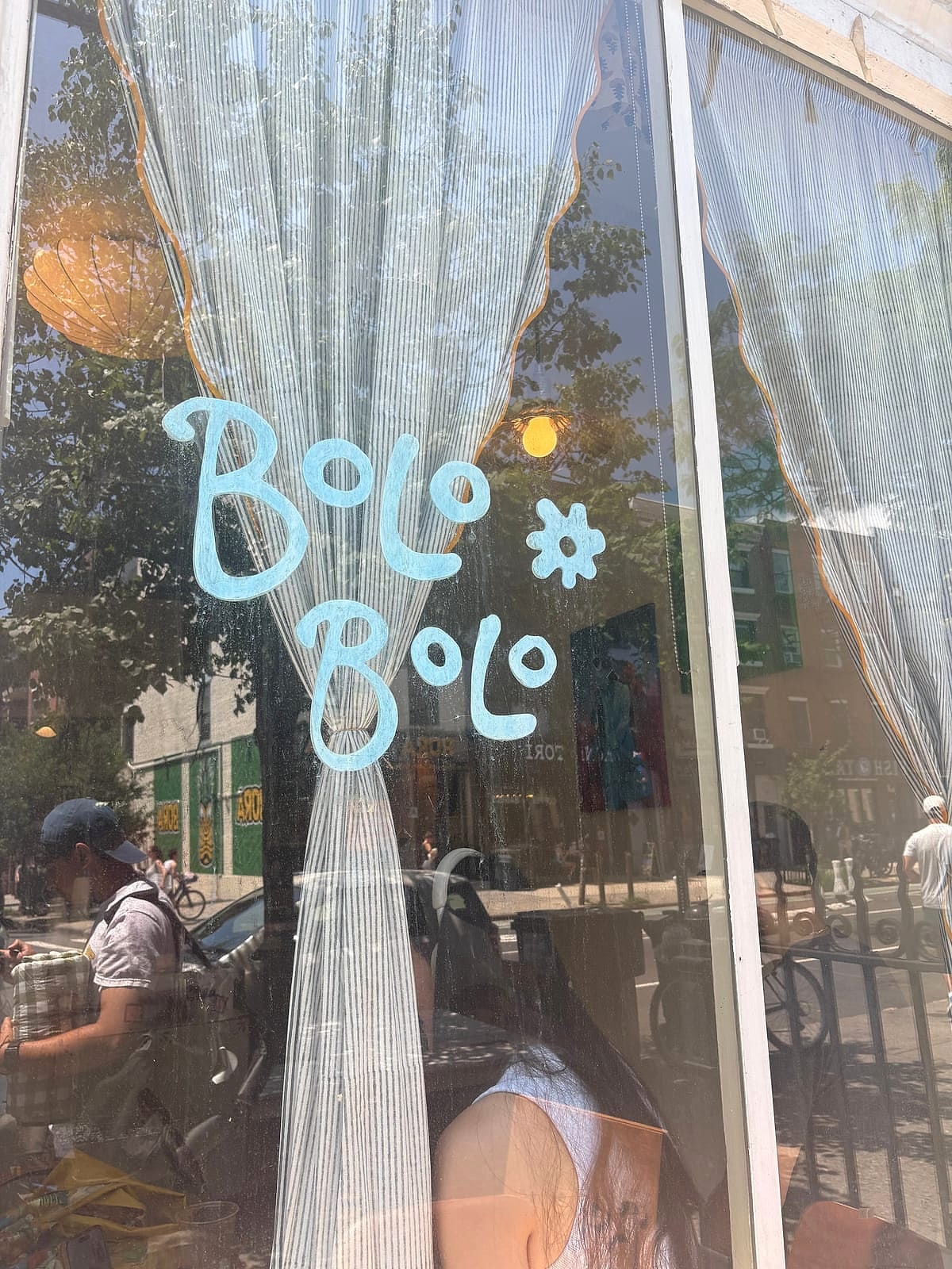 Bolo Bolo's name painted on the cafe window behind lace curtains