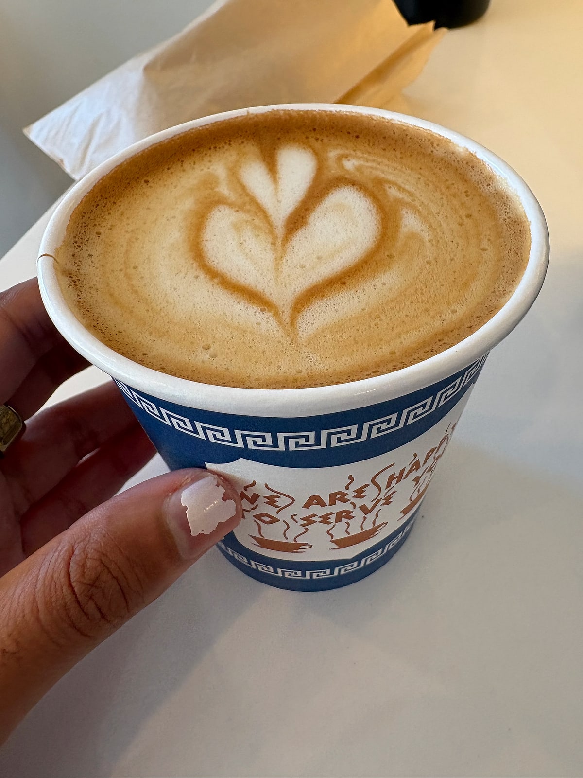 A latte with heart latte art in a classic blue and white New York coffee cup