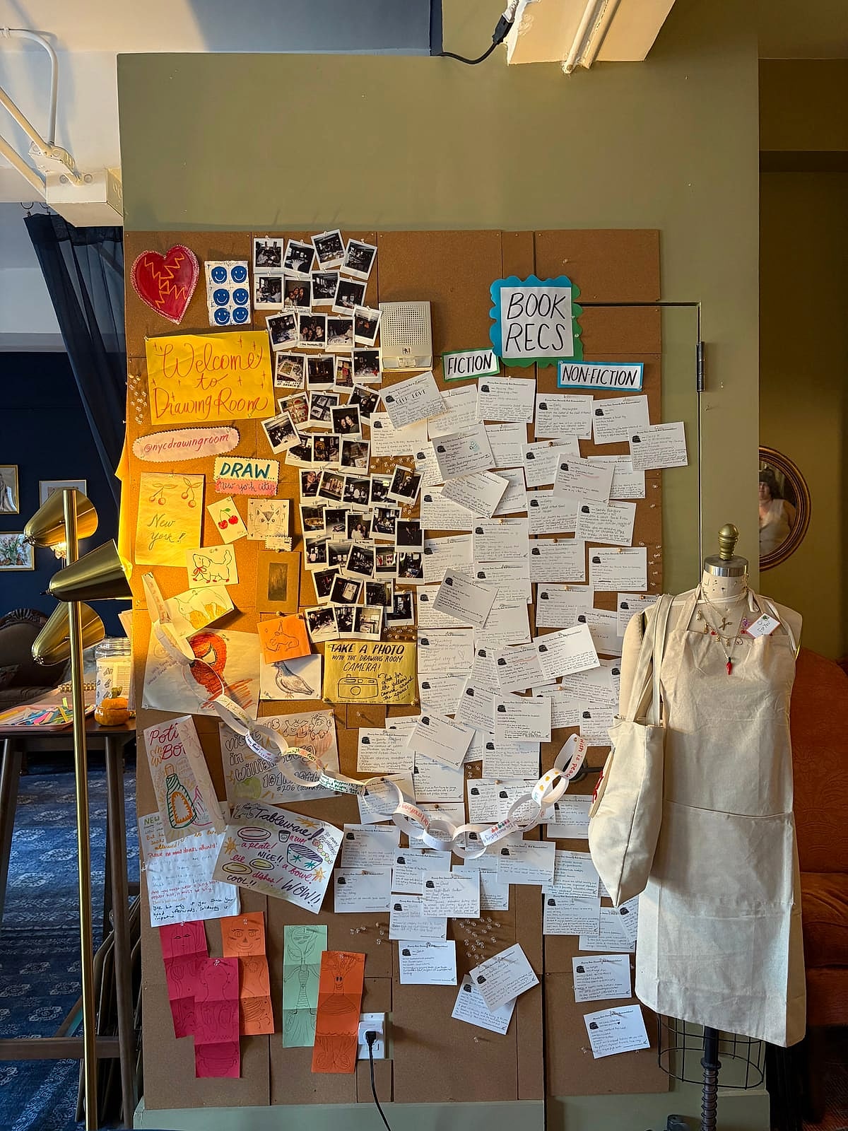 A wall of notes, sketches and polaroids pinned up by visitors