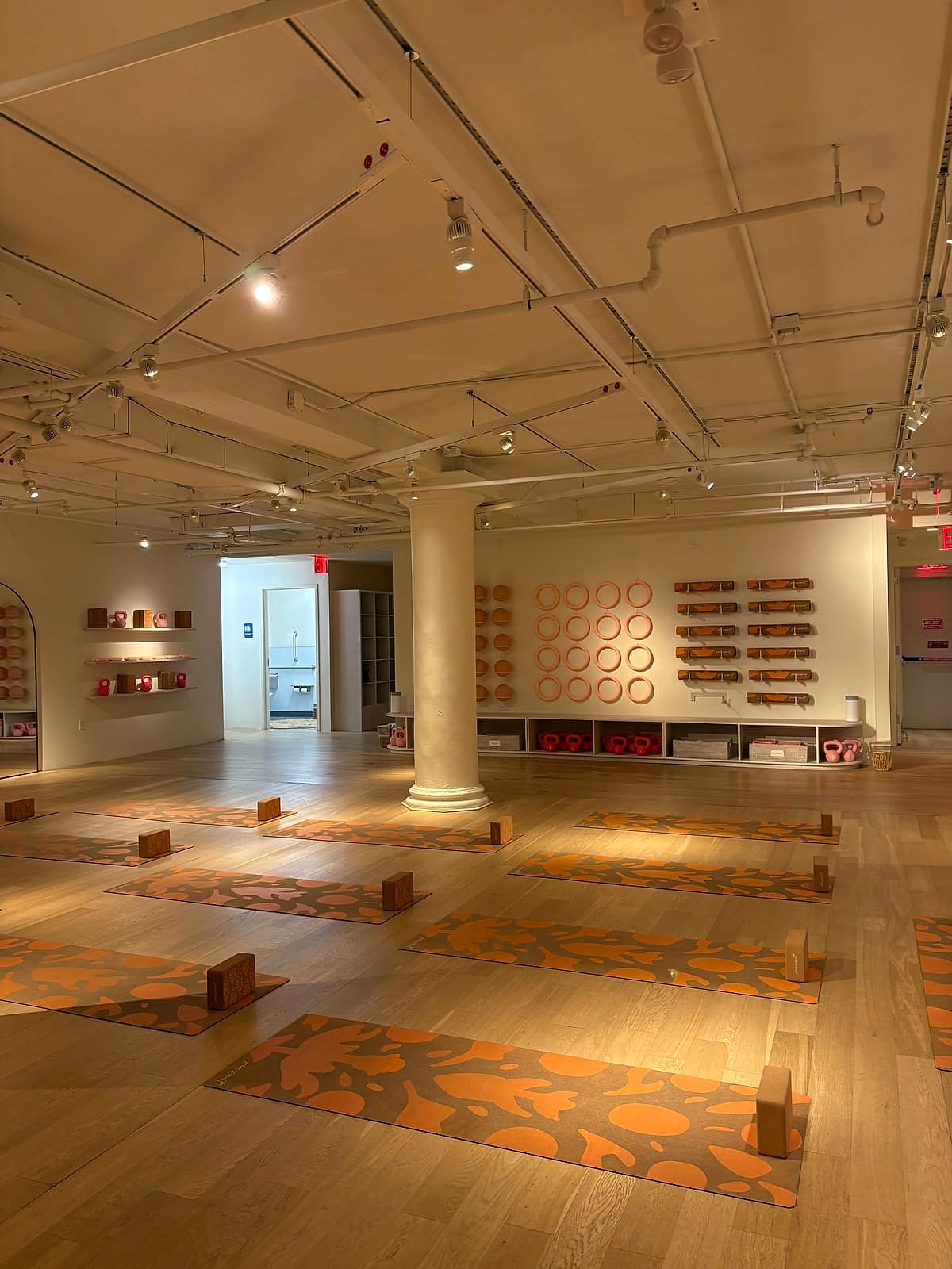 A bright studio with patterned orange mats laid out for class