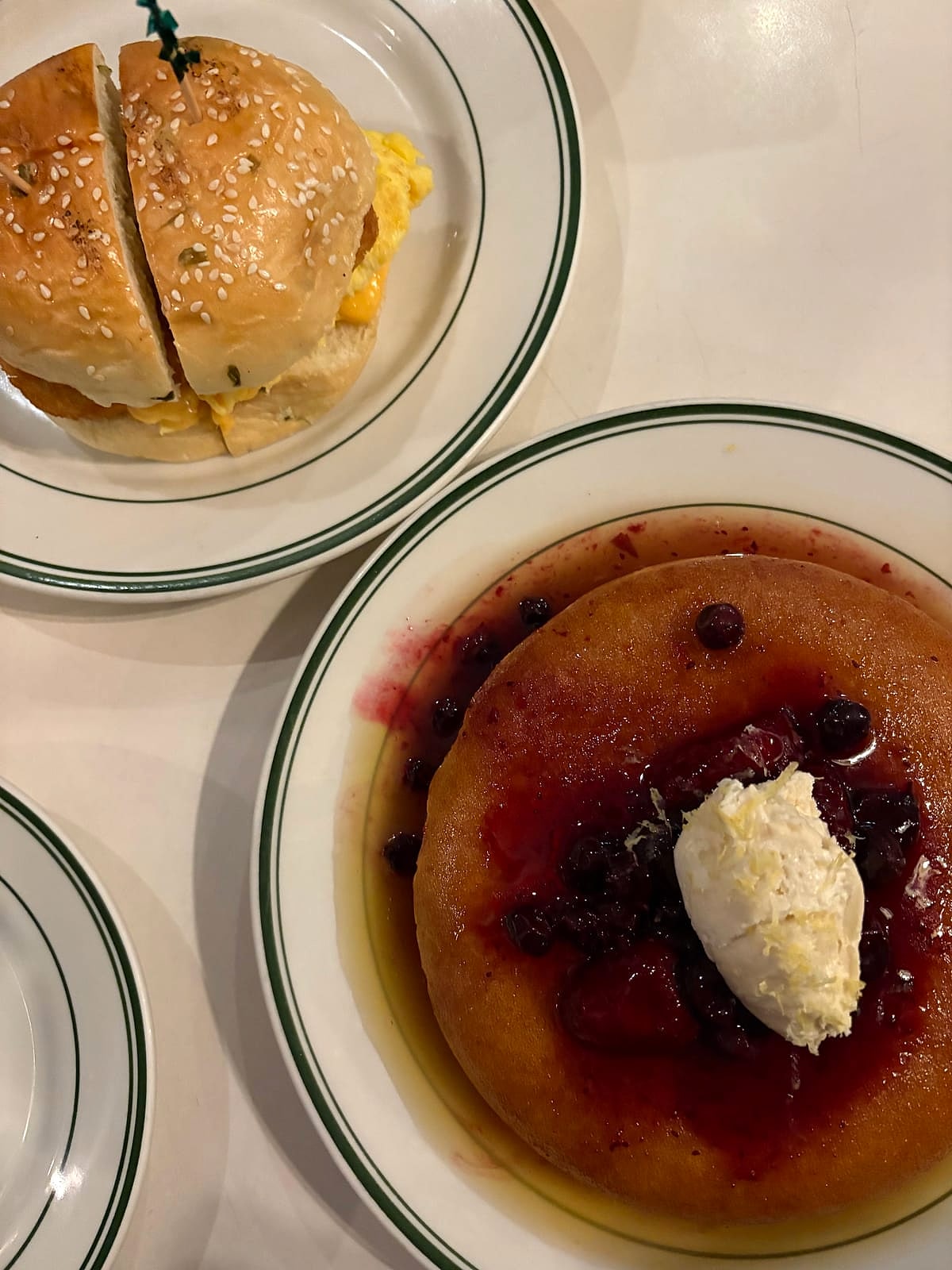 Honey butter pancakes with berry compote next to a breakfast sandwich