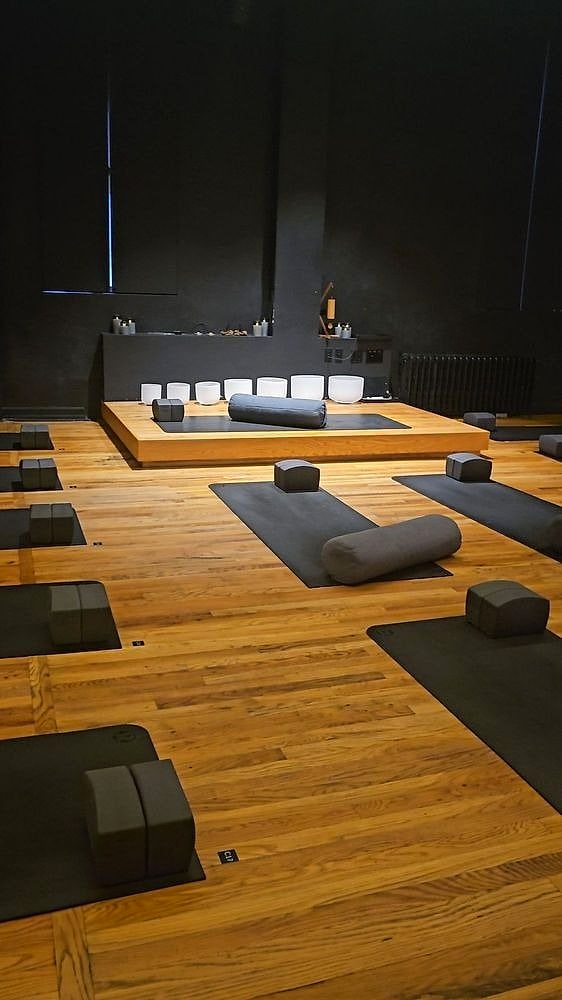 A warm wooden studio set with mats, blocks and bolsters before class