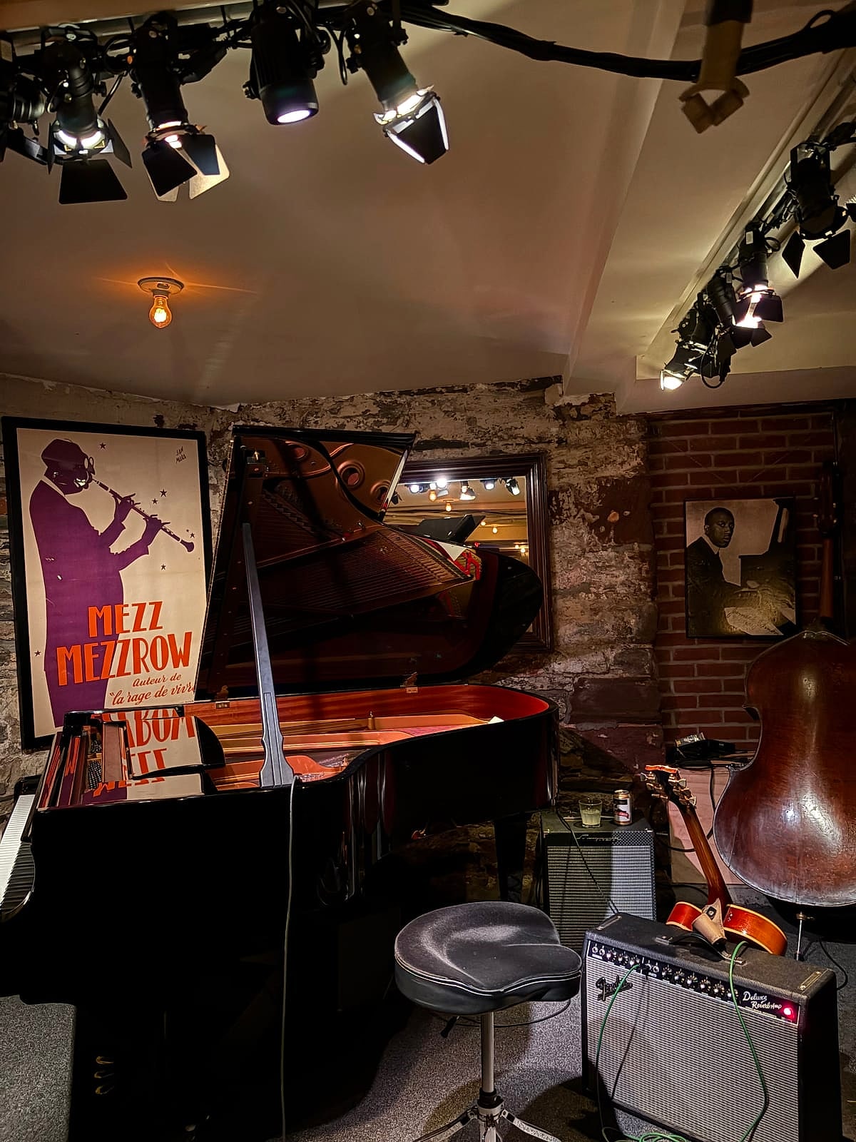 A small jazz club stage with a grand piano and an upright bass