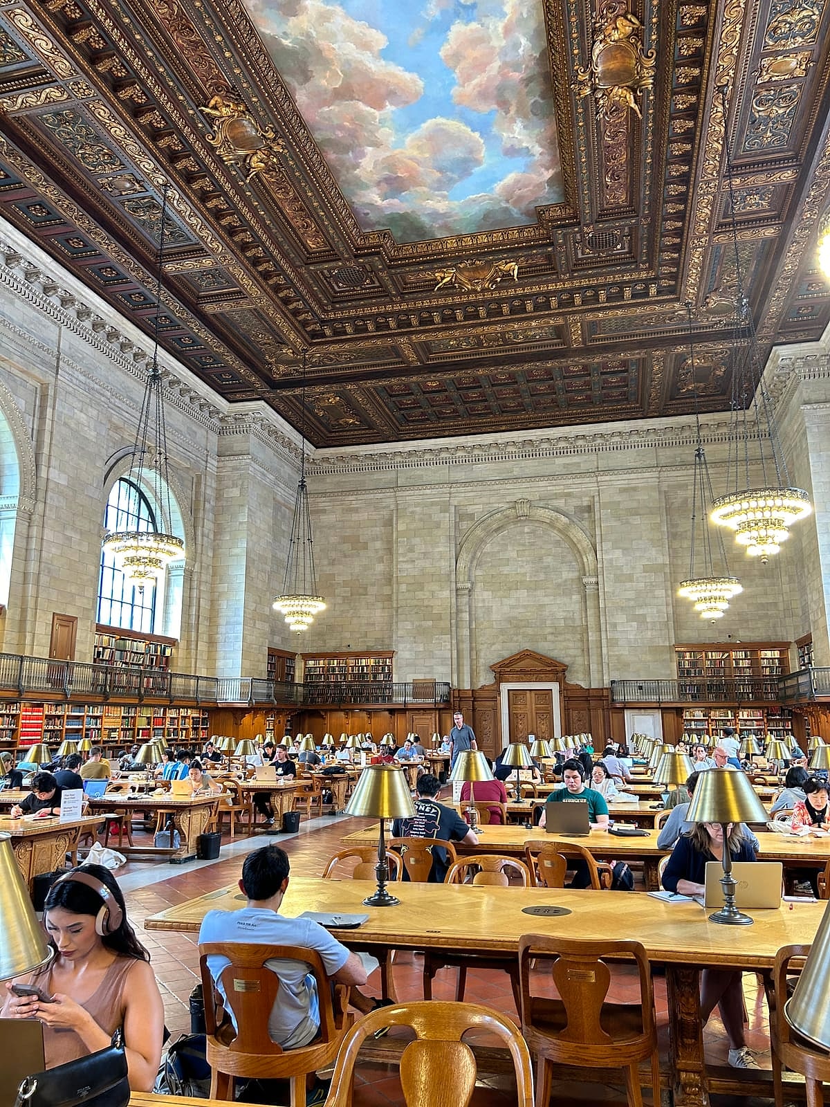 The library's grand reading room, with long wooden tables under a painted ceiling