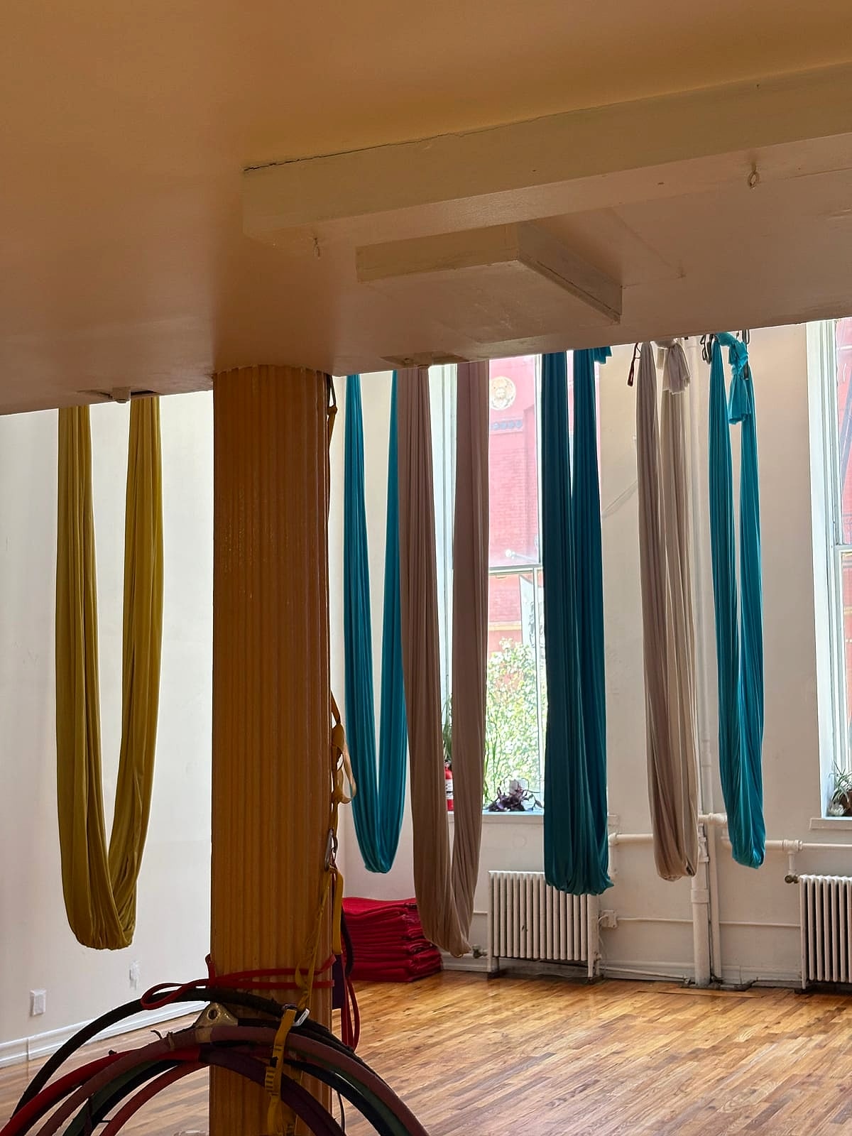 Aerial yoga hammocks hanging in a sunlit studio