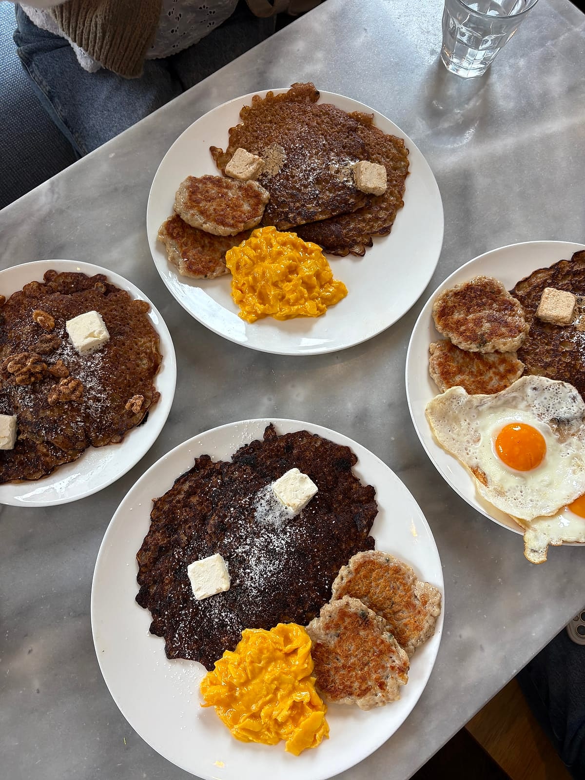 Plates of oatmeal pancakes with butter, eggs and sausage patties