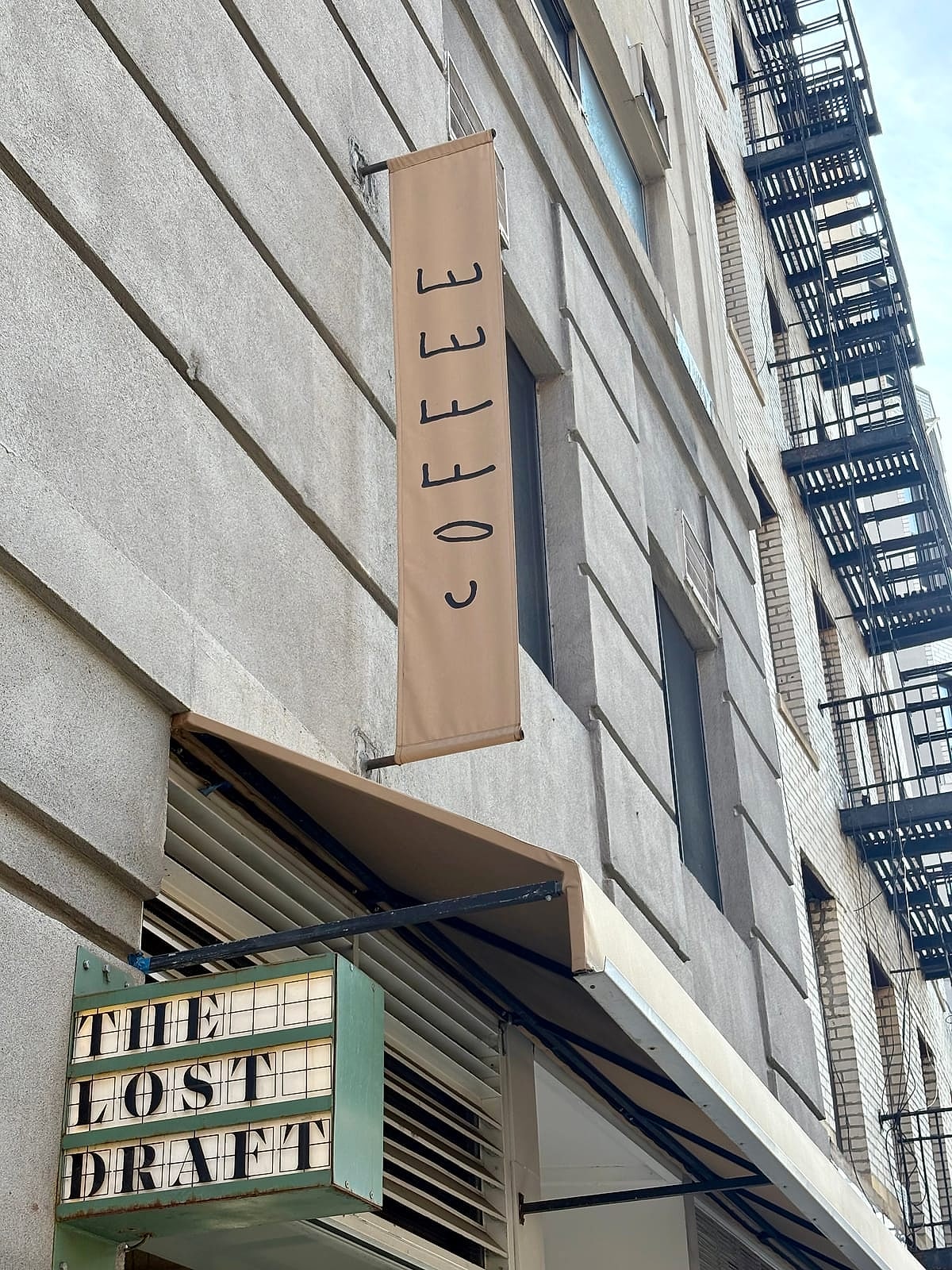 The Lost Draft's green sign and coffee banner on a brick building