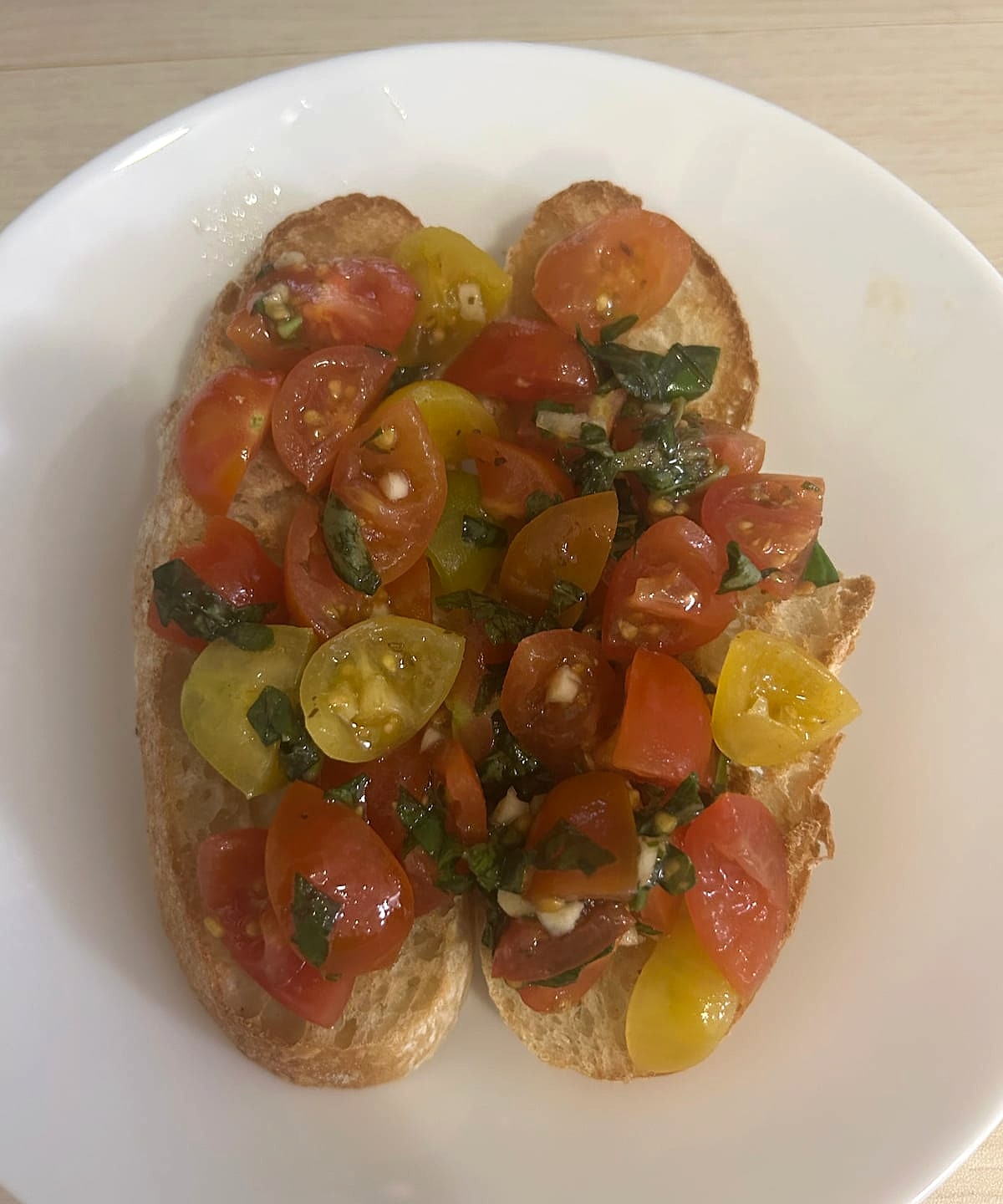 Toasted bread topped with red and yellow cherry tomatoes and basil