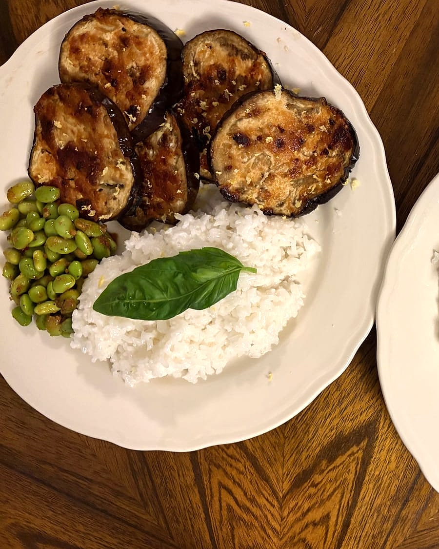 Miso-glazed eggplant rounds with rice, edamame and a basil leaf