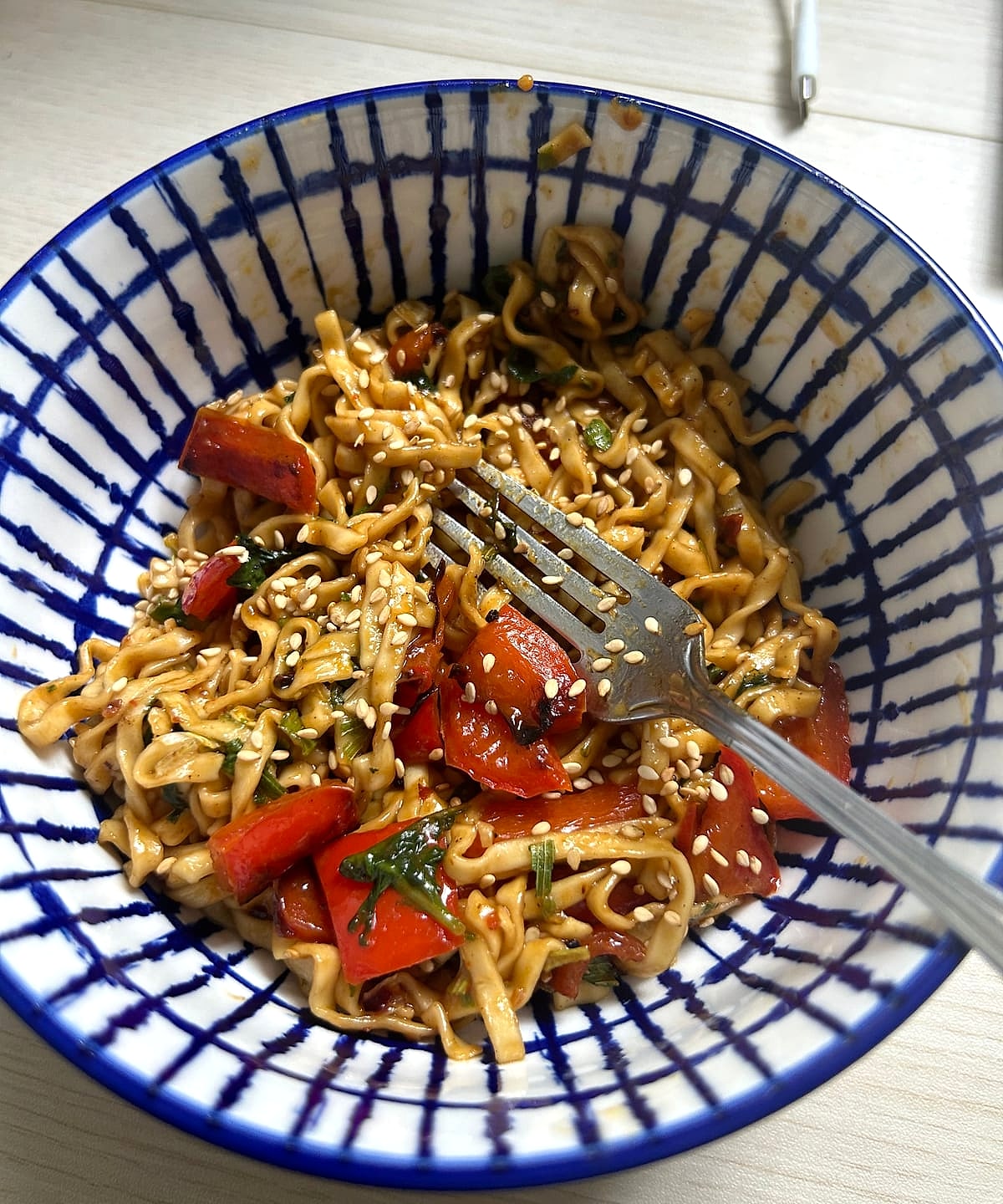 Sesame noodles with red peppers in a blue and white bowl